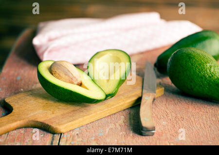 Il dimezzati gli avocadi sul vecchio tavolo in legno Foto Stock