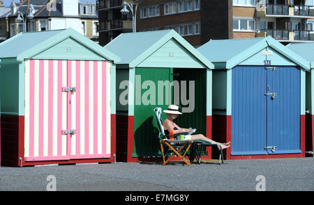 Hove, Brighton, Sussex, Regno Unito. Il 21 settembre 2014. Una donna che legge un libro con la sua capanna sulla spiaggia lungo il lungomare Hove in wather caldo Foto Stock