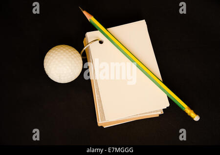 La pallina da golf con i notebook score card su sfondo nero Foto Stock