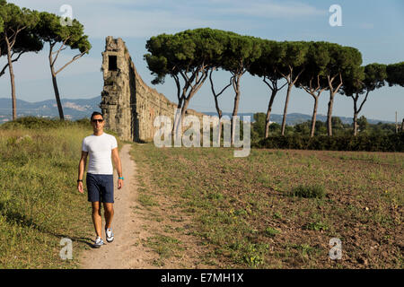 Uomo che indossa una t-shirt bianca con passeggiate in sette acquedotti area in estate, Via Appia Antica di Roma, Italia Foto Stock