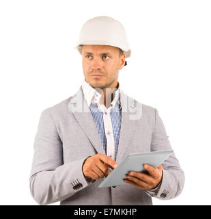 Considerato grave un architetto o un ingegnere che indossa un casco e tenendo un computer tablet guardando fuori alla sua destra con un espressione pensieroso, isolato su bianco. Foto Stock