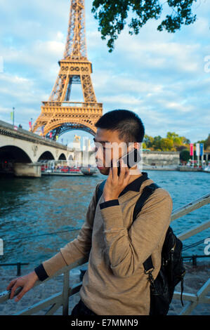 parigi, Francia, giovane uomo cinese, Ritratto, uso di smartphone i-Phone, Telefono, vicino alla Torre Eiffel, Fiume Senna, RITRATTO DI RAGAZZO SU STRADA Foto Stock