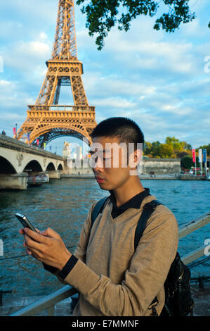 Parigi, Francia, giovane uomo cinese, Ritratto, utilizzando i-Phone Smart Phone, telefono, vicino alla Torre Eiffel, la Senna Foto Stock