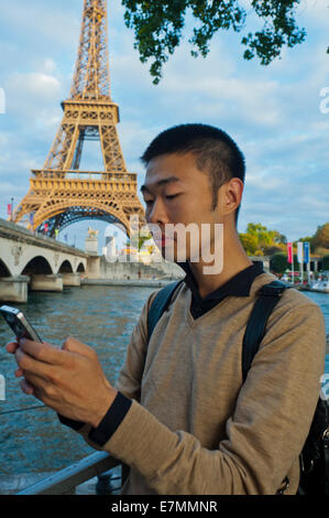 parigi, Francia, giovane uomo cinese, Ritratto, uso di smartphone i-Phone, Telefono, vicino alla Torre Eiffel, sulla Senna RITRATTO DI RAGAZZO SU STRADA Foto Stock