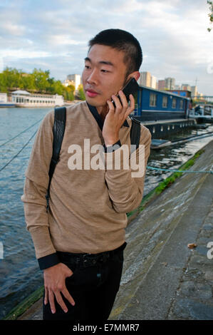 parigi, Francia, Young Chinese Man, Ritratto, utilizzo di iPhone smartphone telefono, esterno, studente Francia, parigi comunità cinese, RITRATTO DI GUY Foto Stock