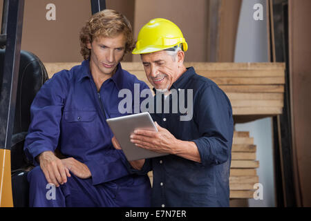 Carpenter con tavoletta digitale con un collega Foto Stock