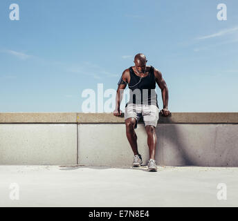 Muscolare di giovane uomo di prendere fiato dopo la sua esecuzione. Africa atleta maschio all aperto con copia spazio. Runner maschio rilassante dopo runnin Foto Stock