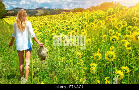 Felice giovane donna camminare nel nuovo campo di girasoli, il paesaggio agricolo, natura autunnale, la stagione del raccolto di concetto Foto Stock