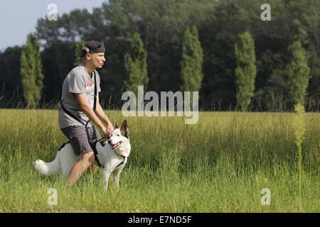 Il ragazzo bianco e il suo cane bianco di razza mista in campagna, durante una calda giornata estiva in Italia. Foto Stock