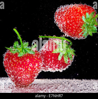 Fragola con bolle in acqua di soda su sfondo nero Foto Stock