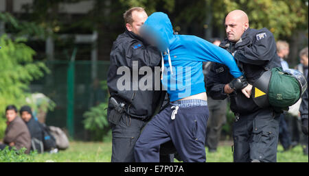 Berlino, Germania. Il 22 settembre, 2014. Berlino, Germania. Il 22 settembre, 2014. Gli ufficiali di polizia cattura di un giovane uomo sulla sede urbana conosciuta come Cuvry-Brache dove i sostenitori ed ex residenti impostare camp a Berlino, Germania, 22 settembre 2014. A causa di un incendio i residenti sulla Cubvry-Brache furono costretti a lasciare la loro sistemazione. Il danneggiato capanne improvvisate e rimane ora vengono spinte su un palo. Le cadute, i rifugiati e le famiglie di Roma aveva preso la residenza sulla Cuvry-Brache negli ultimi anni, un urbano locali che non è stata oggetto di proprietà di sviluppo. Foto: Bernd von Jutrcze Foto Stock