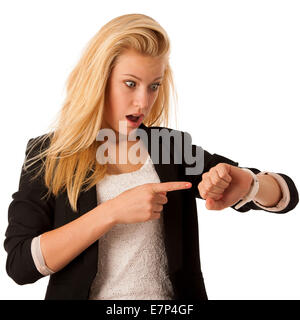 Giovane donna bionda che guarda al suo orologio quando essa è in fase di fine isolate su sfondo bianco Foto Stock