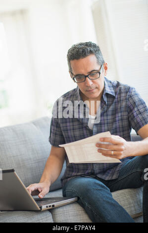 Uomo che fa delle finanze personali con il computer portatile Foto Stock