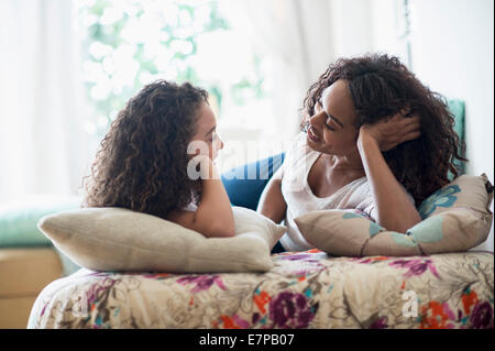 Madre e figlia (8-9) la conversazione sul letto Foto Stock