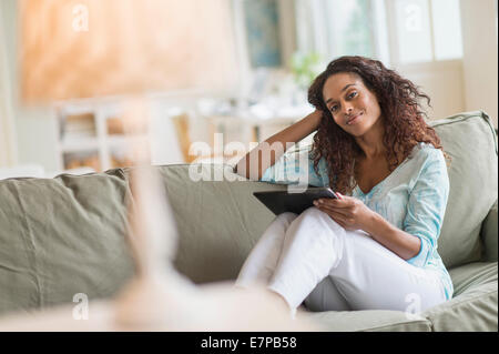 Donna con tavoletta digitale sul divano Foto Stock