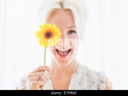 Ritratto di donna bionda azienda fiore giallo Foto Stock