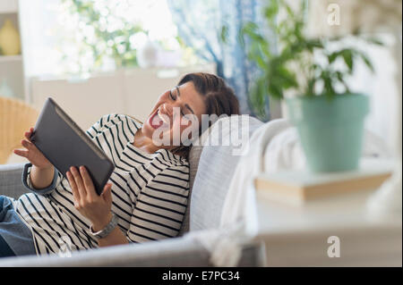 Ritratto di donna felice sdraiato sul divano con i tablet pc Foto Stock