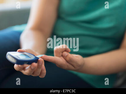 Donna seduta su un divano con il telefono cellulare Foto Stock