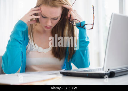 Frustrati giovane donna guardando le bollette Foto Stock