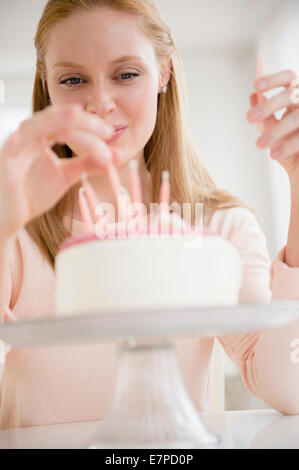Donna mettendo candele sulla torta di compleanno Foto Stock