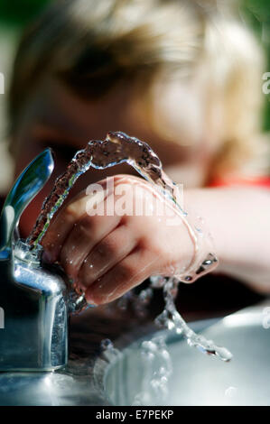 Un giovane ragazzo (2 1/2 anni) giocando con una fontana di acqua Foto Stock