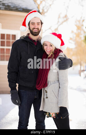 Stati Uniti d'America, Utah, Salt Lake City, Ritratto di giovane coppia cappelli di Babbo Natale davanti a casa Foto Stock