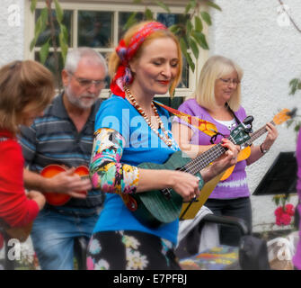 Lo stile di vita del Regno Unito: Colorful persona di sesso femminile in un ukulele orchestra band - che si diverte in un gruppo di musica Foto Stock