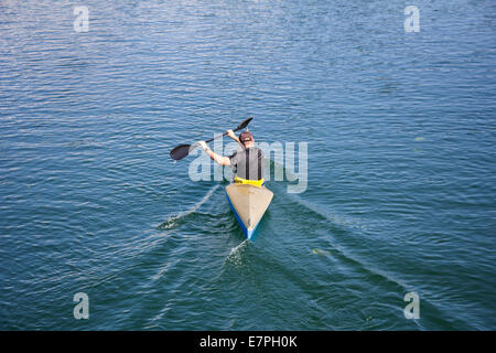 Uomo in una canoa e canottaggio sul lago tranquillo Foto Stock