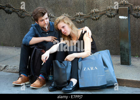 Coppia di shopping a Praga che riposa dopo aver fatto shopping sotto il monumento di St Venceslao, Praga Repubblica Ceca popolo Zara sacchetti di carta giovane donna triste Foto Stock