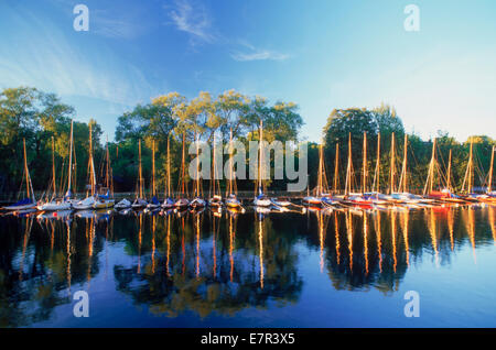 Lunga fila di barche a vela ormeggiata in sunrise riflettente la luce spenta Langholmens Canal o Långholmen a Stoccolma Svezia Foto Stock