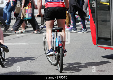 Articoli di cancelleria per i ciclisti e un bus in attesa ad un semaforo mentre i pedoni attraversare la strada Foto Stock