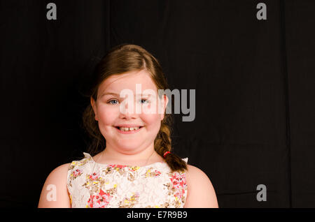 Immagine di una bimba di 8 anni, su uno sfondo nero con un sorriso Foto Stock