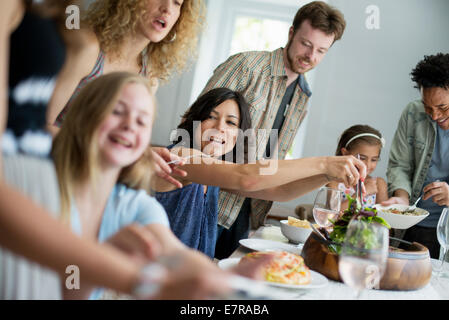 Una riunione di famiglia per un pasto. Adulti e bambini intorno a un tavolo. Foto Stock