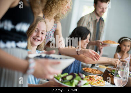 Una riunione di famiglia per un pasto. Adulti e bambini intorno a un tavolo. Foto Stock