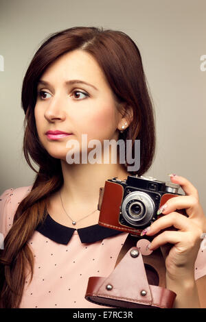 Tanga giovane donna fare una fotografia con la vecchia telecamera. Calda tonalità del colore dell'immagine. Foto Stock