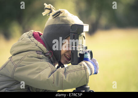 Carino piccolo ragazzo riprese di una fotografia in autunno park Foto Stock