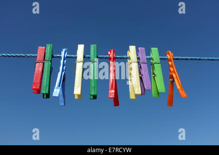 Clothespin multicolore appeso su un cavo blu Foto Stock