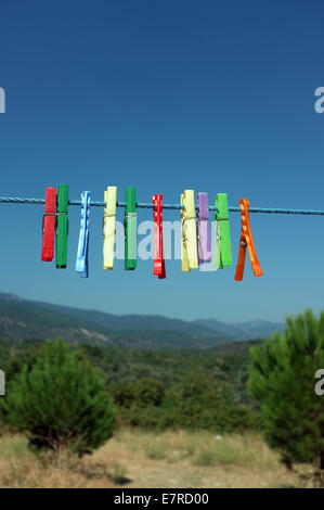 Clothespin multicolore appeso su un cavo blu Foto Stock