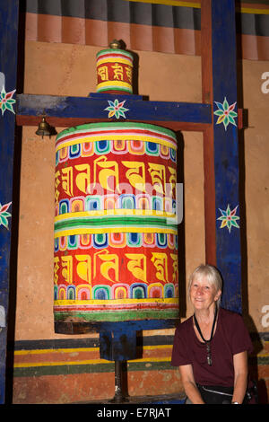 Il Bhutan orientale, Trashi Yangtse, old Dongdi Dzong, femmina turistico a decorato dipinto ruota di preghiera Foto Stock