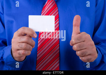 Imprenditore con cravatta rossa e maglietta blu holding e mostra vuoto bianco, business card con approvazione, sì segno. Foto Stock