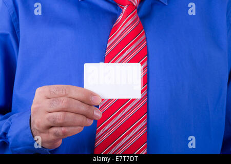 Imprenditore con cravatta rossa e maglietta blu holding e mostra vuoto bianco, business card. Foto Stock