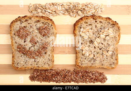 Semi di lino e farina di avena nella forma della faccia su fette di pane integrale, concept per una sana alimentazione Foto Stock