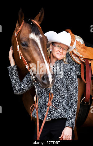Quarter Horse, bay castrazione, torneo vestito con una femmina di Western rider, in corrispondenza di una Wild West Show Foto Stock