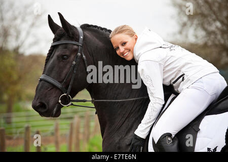 Il frisone o Frisone cavallo, stallone, inglese briglia, con femmina cavaliere a cavallo Foto Stock