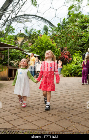 A due 2 anno vecchia ragazza / bambino / bambino / neonato e i suoi quattro 4 anno vecchia sorella a piedi / play all'interno di Progetto Eden biomi. Regno Unito. Foto Stock