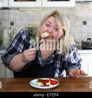 Grande donna in cucina i gusti una cotoletta Foto Stock