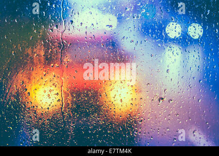 Gocce di pioggia sul vetro azzurro sfondo. Street Bokeh Lights Out di messa a fuoco. Autunno sfondo astratto Foto Stock