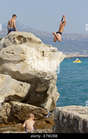 Giovane uomo salta fuori da una scogliera, Split, Dalmazia, Croazia Foto Stock