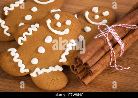 Pane appena sfornato gingerbread man cookies con bastoncini di cannella sul tagliere di legno Foto Stock