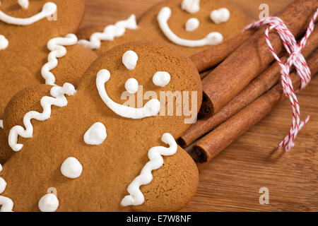 Pane appena sfornato gingerbread man cookies con bastoncini di cannella sul tagliere di legno Foto Stock